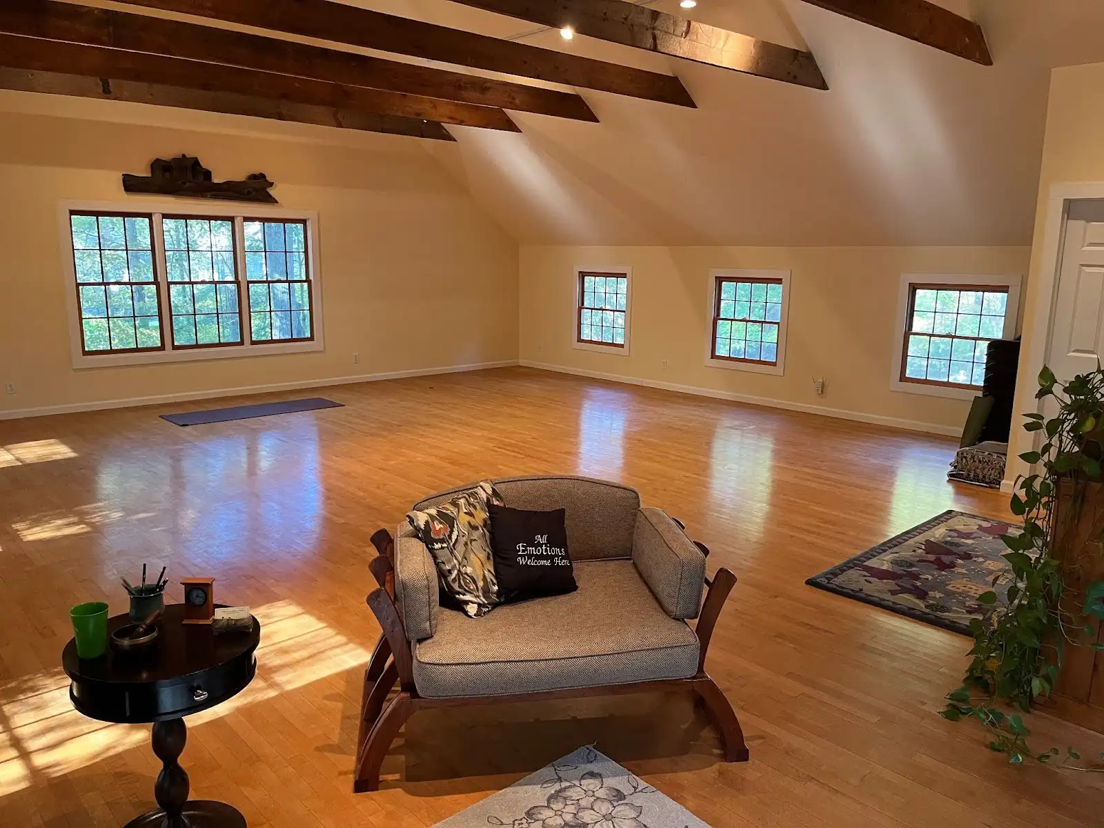 The sunlit Peaceable Barn studio with post-and-beam ceiling, wide-plank floors and windows to the trees